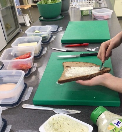 das Bild zeigt Hände, die ein belegtes Brot vorbereitet © Nora Leiner