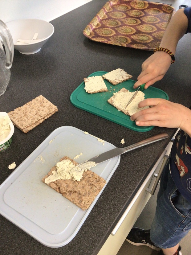 Hände eines Schülers, wie sie Knäckebrot durchschneiden © Nora Leiner